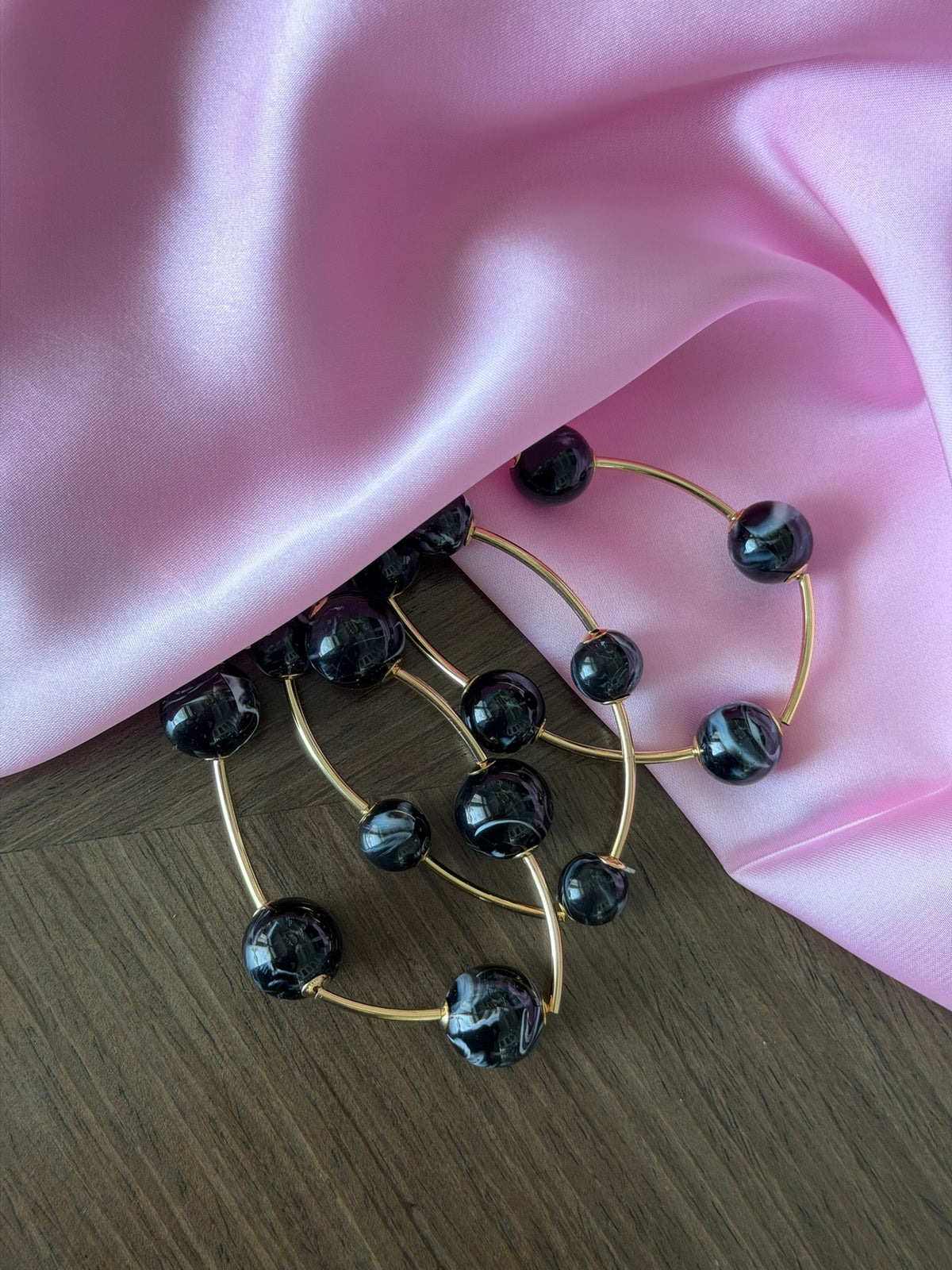 Gold brooch with black beads on a pink fabric background