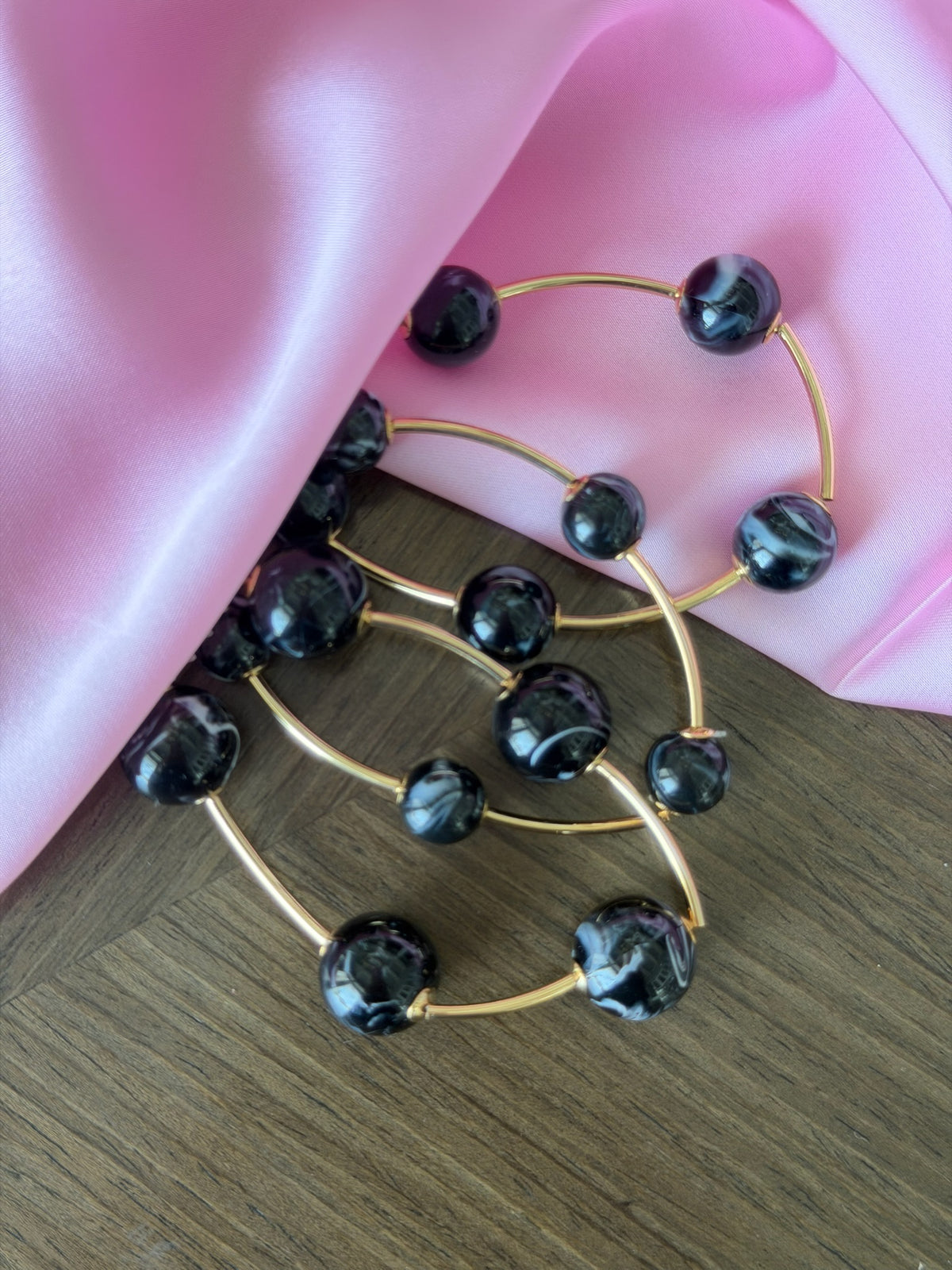 Gold brooch with black beads on a pink fabric background