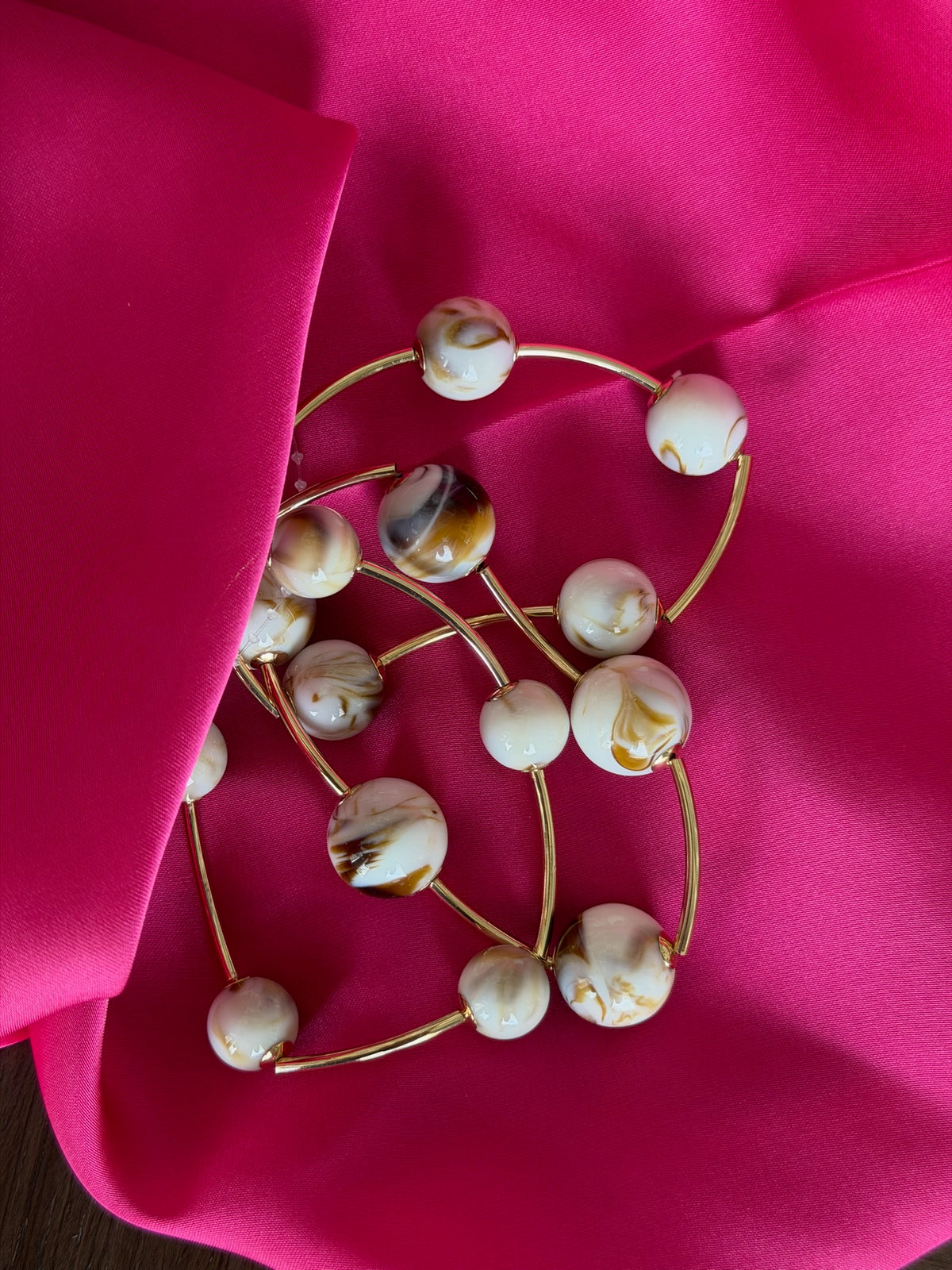 Gold headband with pearl-like beads on a pink fabric background