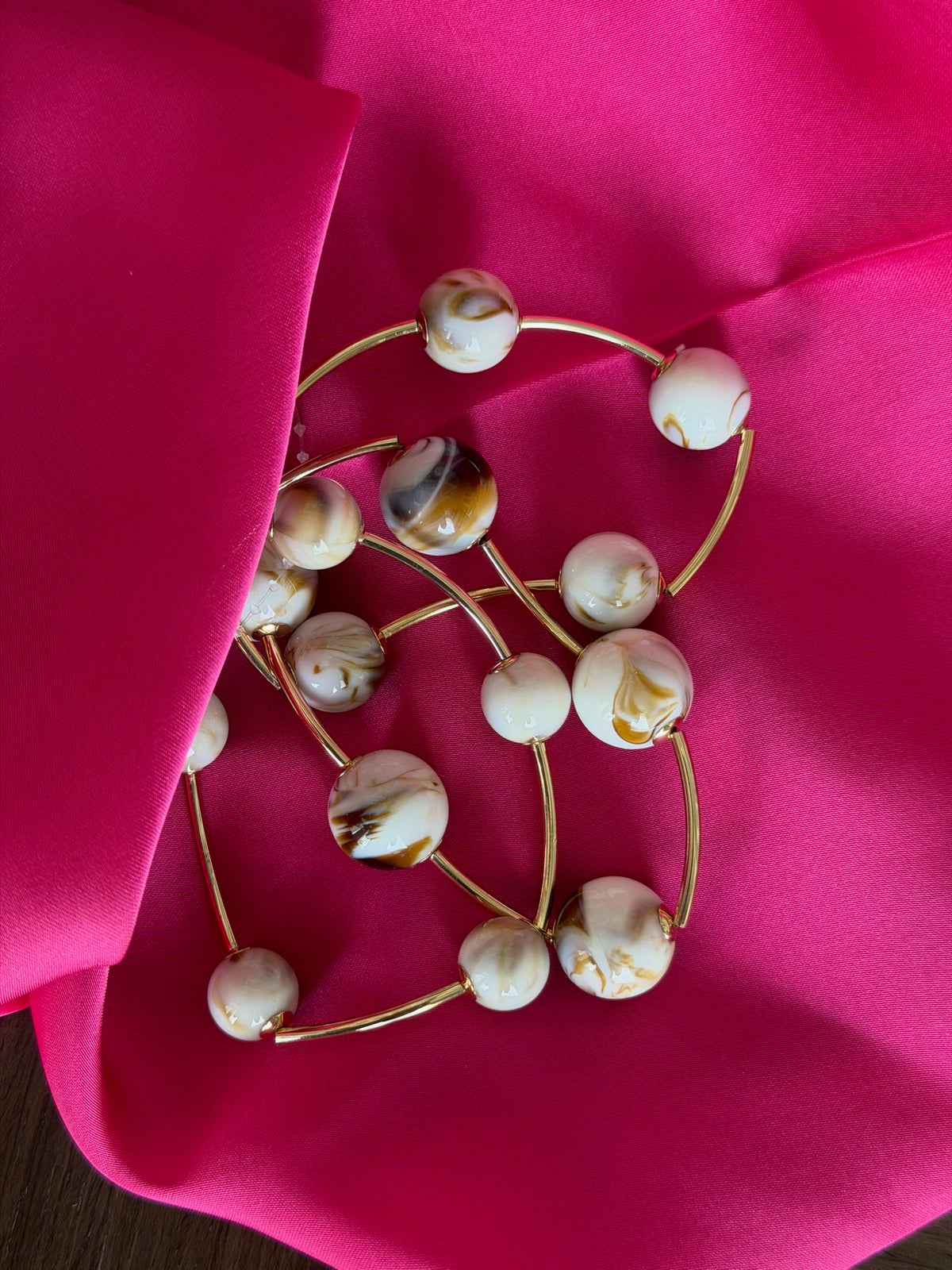 Decorative wreath with white and gold balls on a pink fabric background
