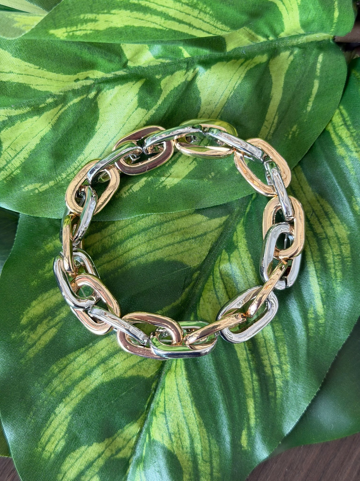Bracelet with gold and silver links on a leafy green background