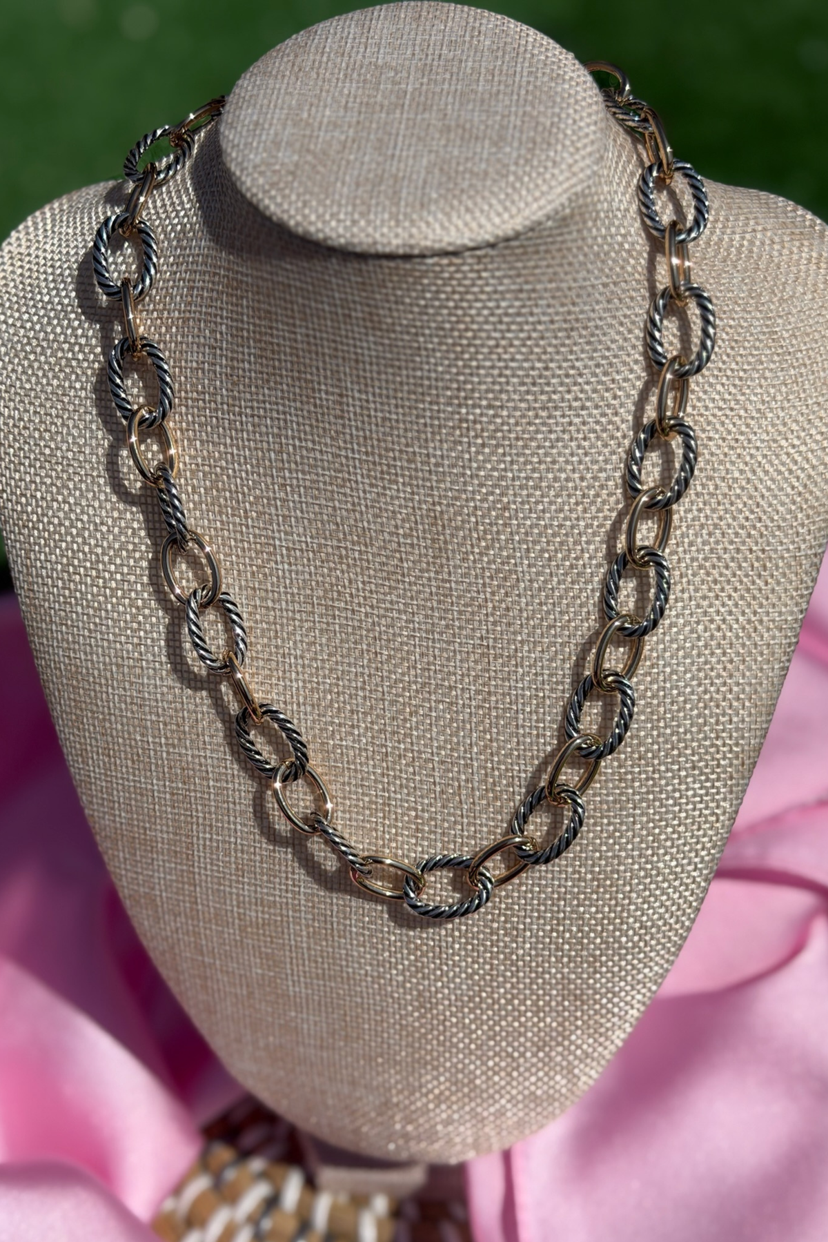 Chain necklace on a mannequin bust with pink fabric background