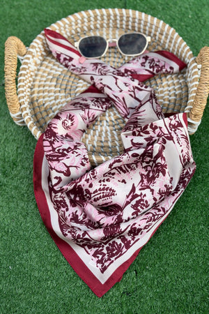 Burgundy scarf sitting on a tan basket with a green turf background.