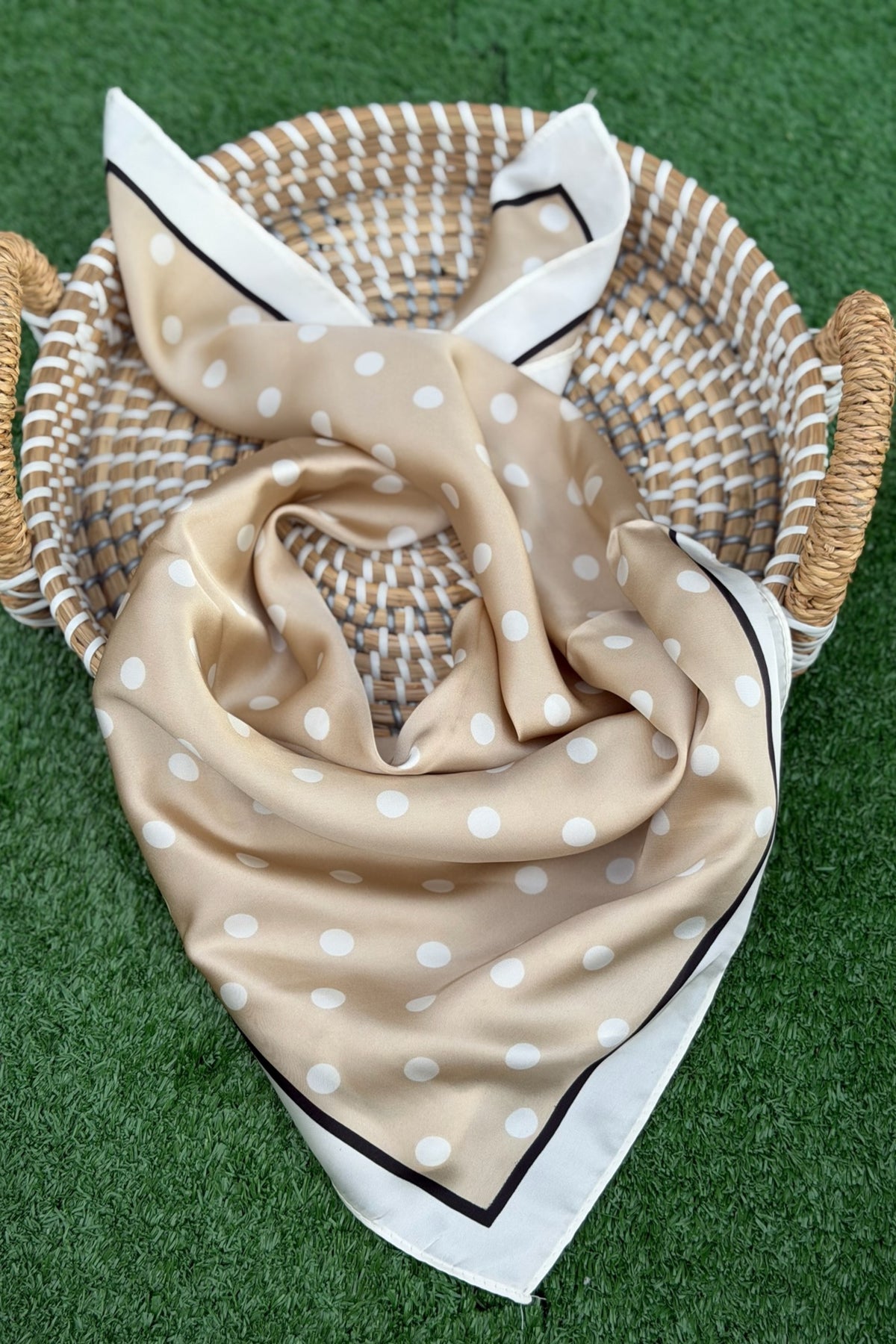 tan with white dots scarf displayed on a tan circular item on a turf ackground.