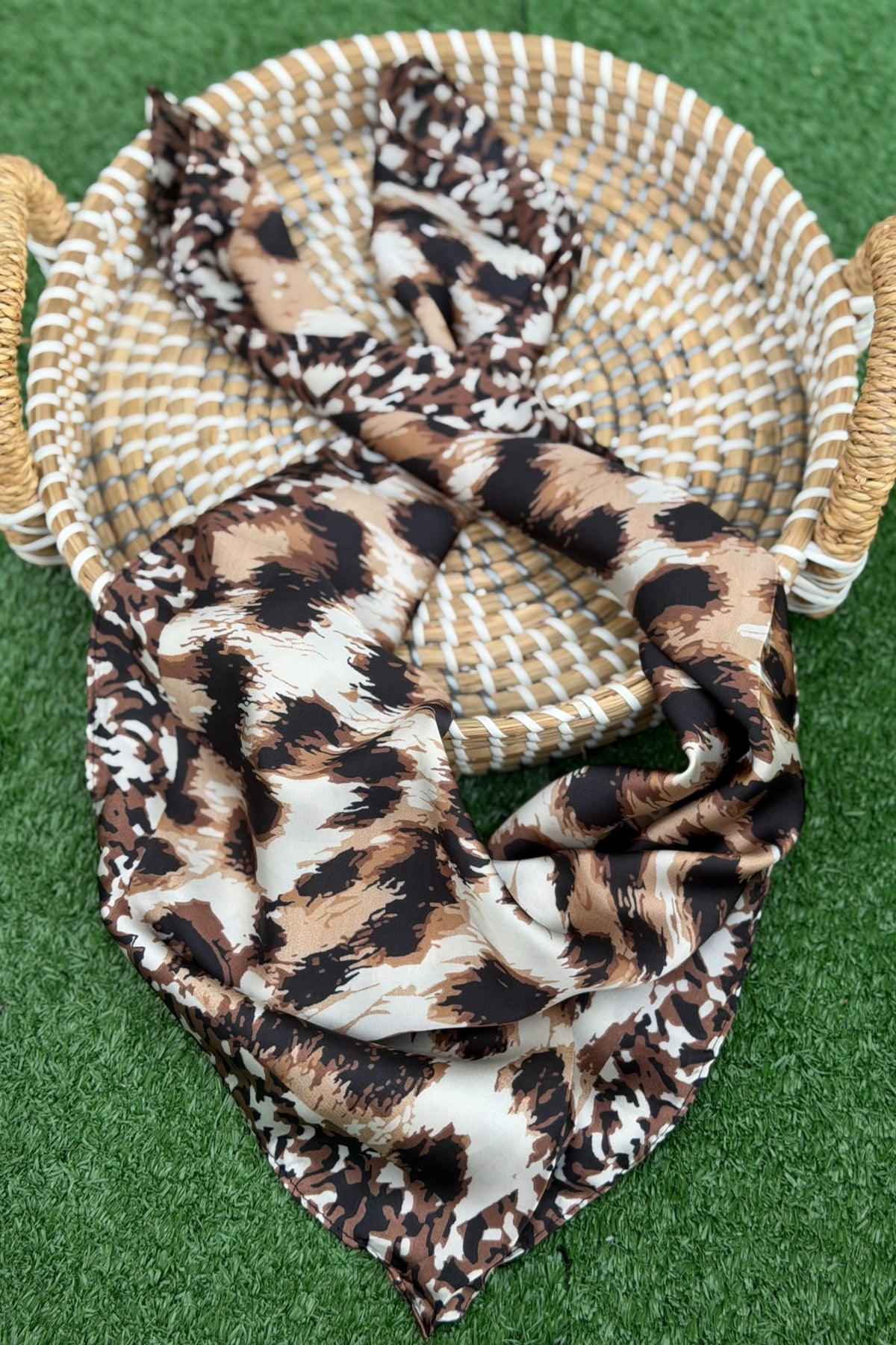 Leopard print fabric draped over a woven basket on a green background