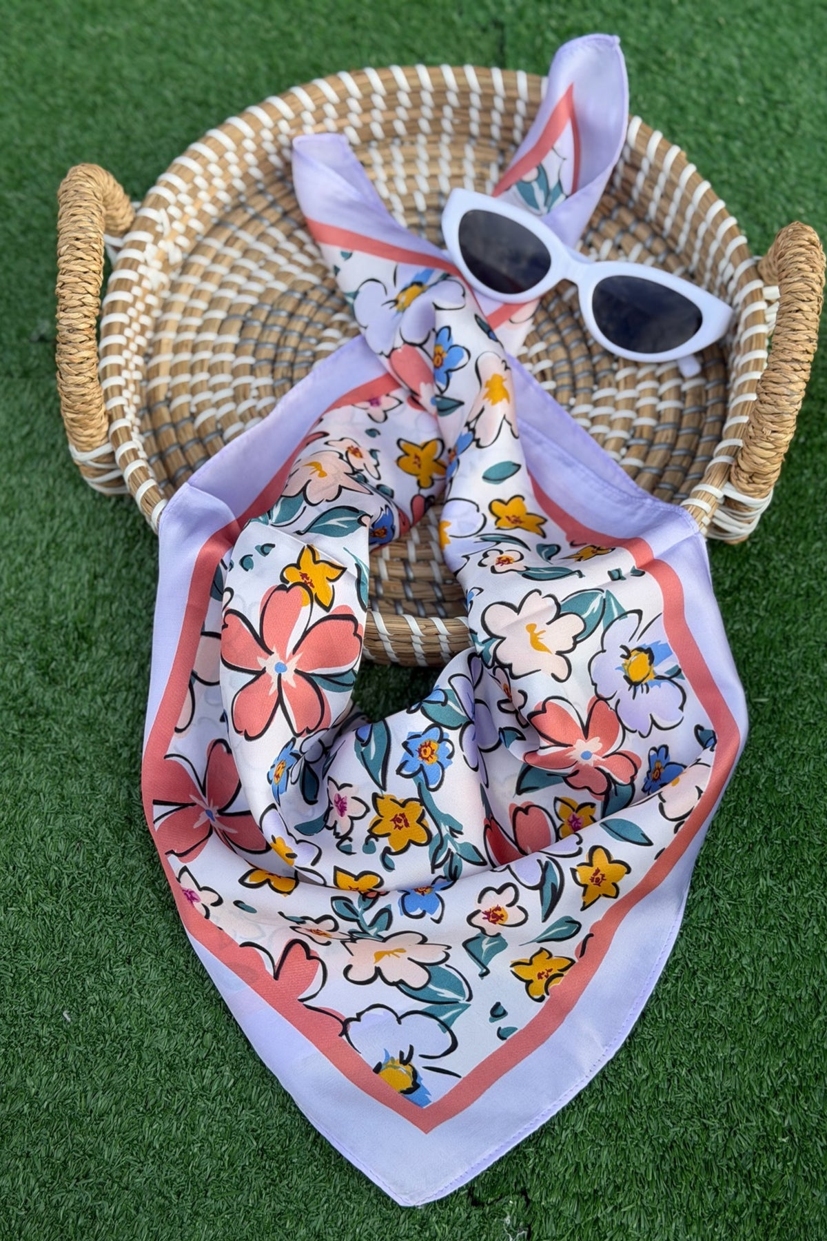 a blue scarf with flowers folded on a tan basket with a green turn background.