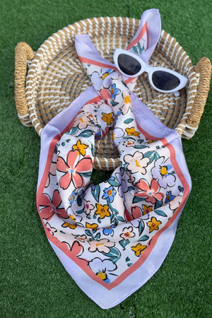a blue scarf with flowers folded on a tan basket with a green turn background.