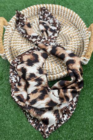 Leopard print fabric draped over a woven basket on a green surface