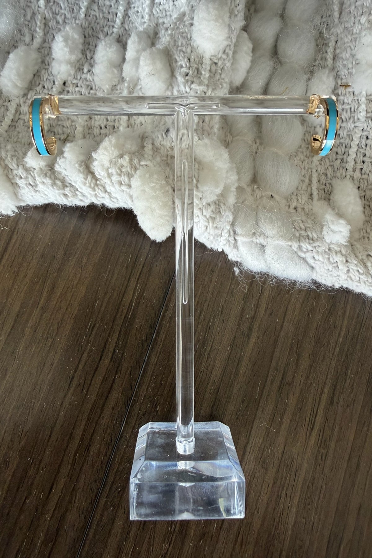 Clear acrylic T-shaped stand on a wooden surface with a textured white background