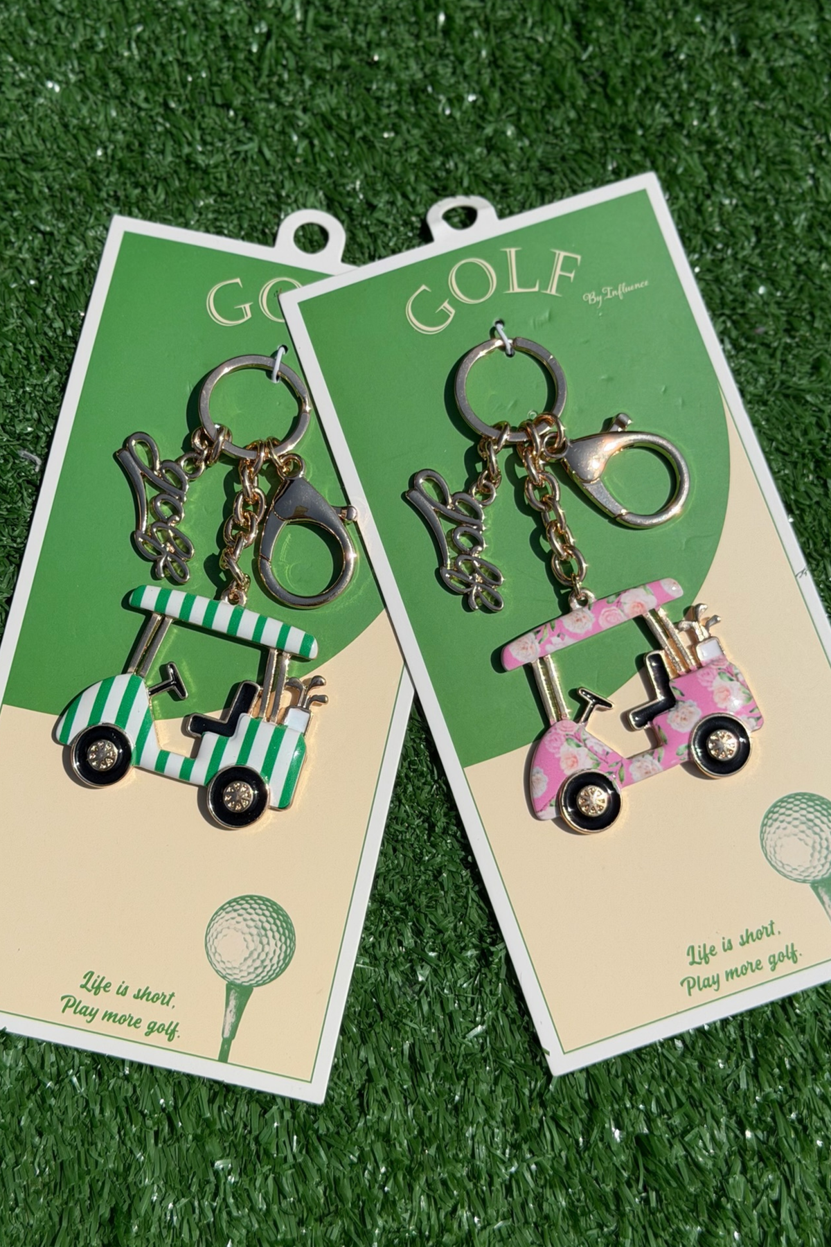Two pairs of golf-themed keychains on green and beige cards with 'GOLF' text, displayed on grass.