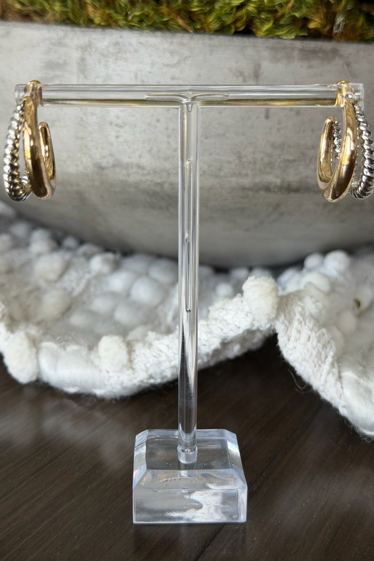 Gold hoop earrings on a clear stand with a natural stone background