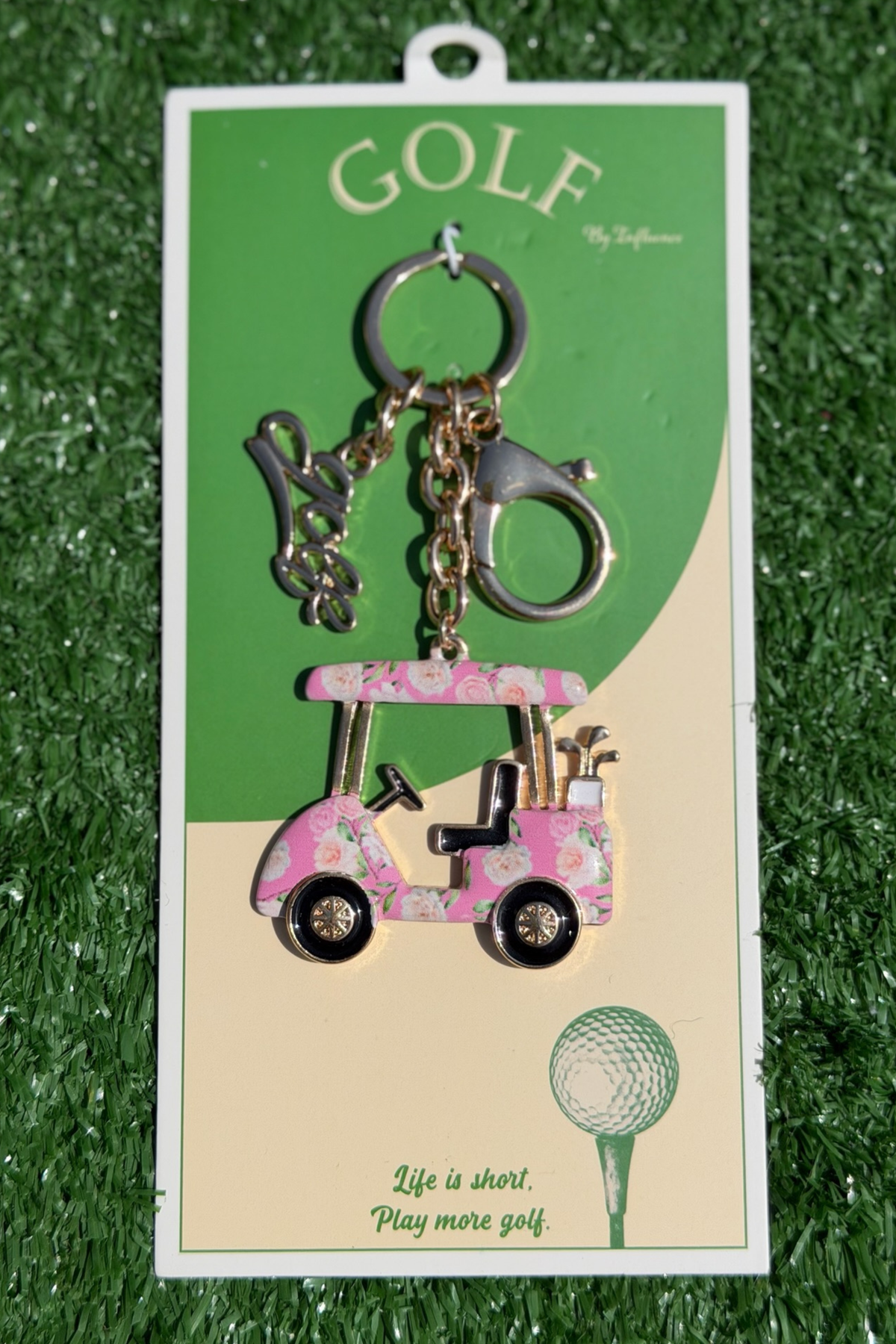Keychain with golf cart design on a green grass background