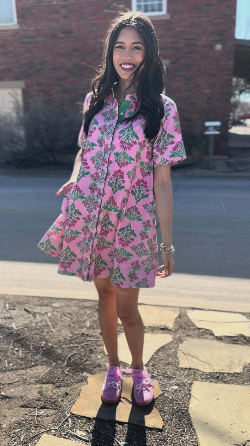 Woman wearing a pink floral dress outside.