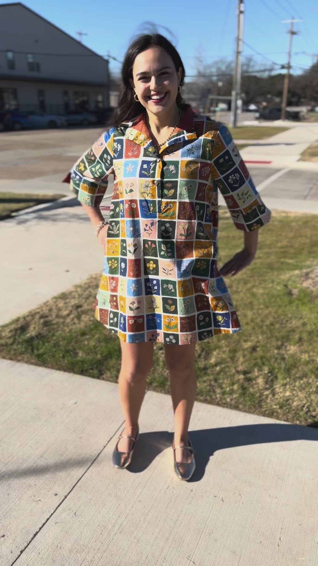 Woman wearing a colorful patterned dress standing outside.
