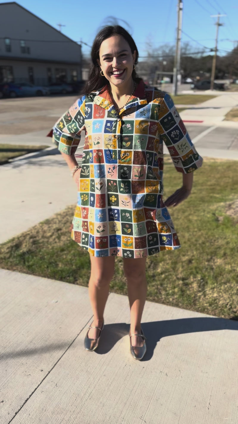 Woman wearing a colorful patterned dress standing outside.