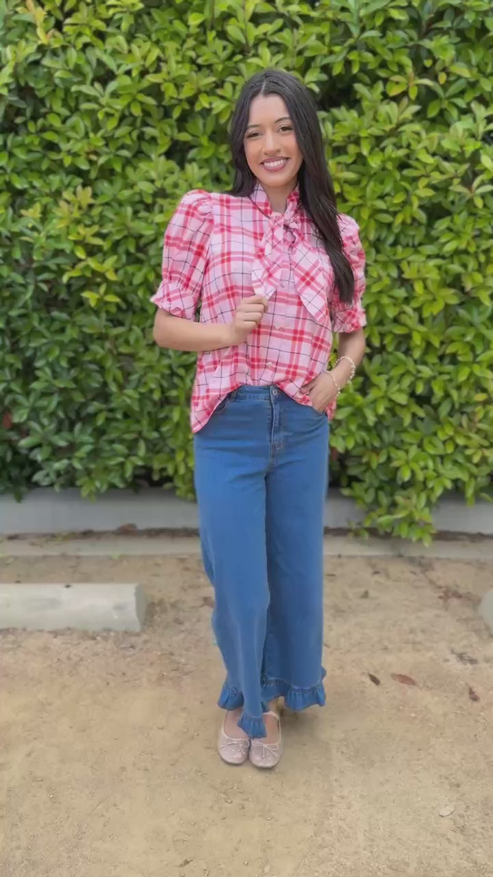 Woman wearing a red plaid shirt and blue jeans outdoors