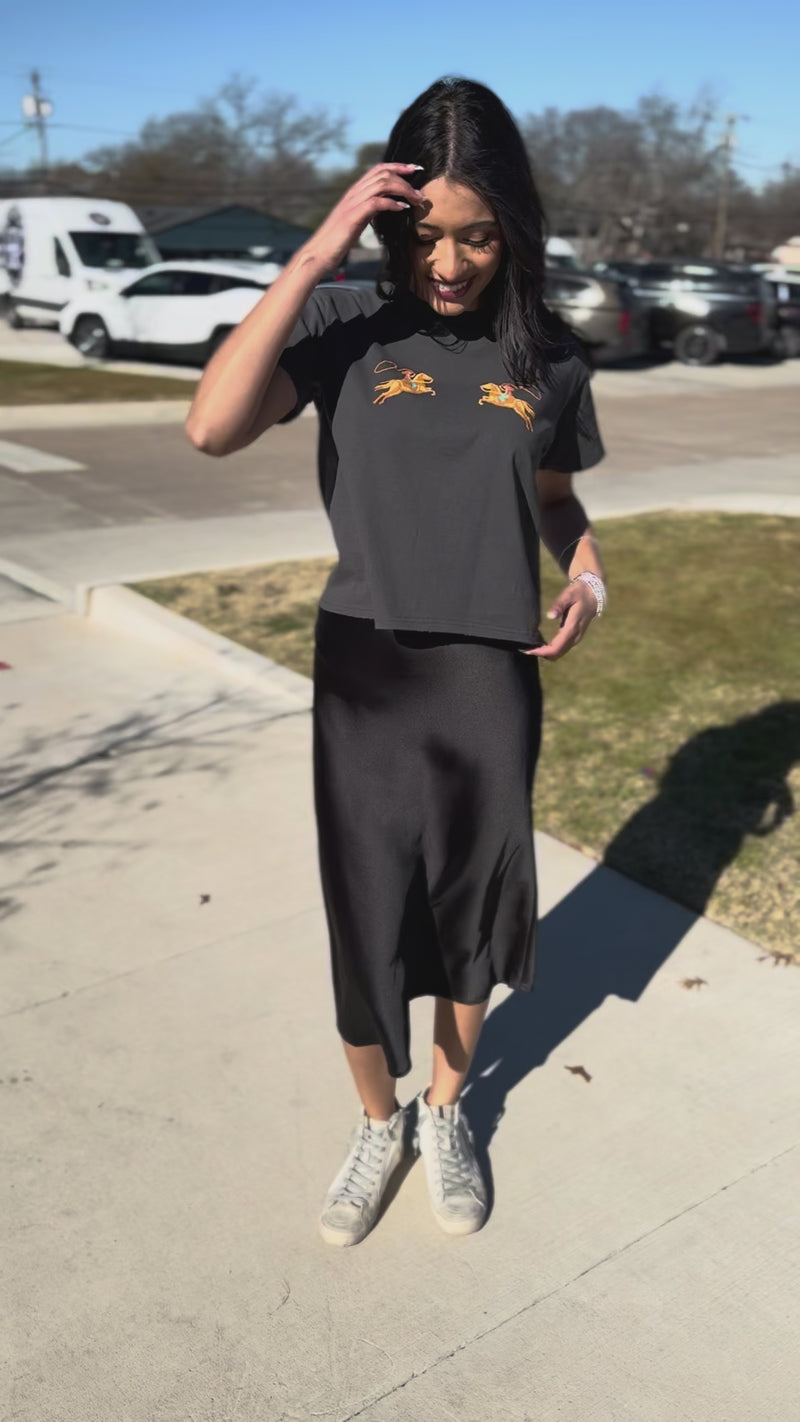 Woman wearing a charcoal shirt and black midi skirt.