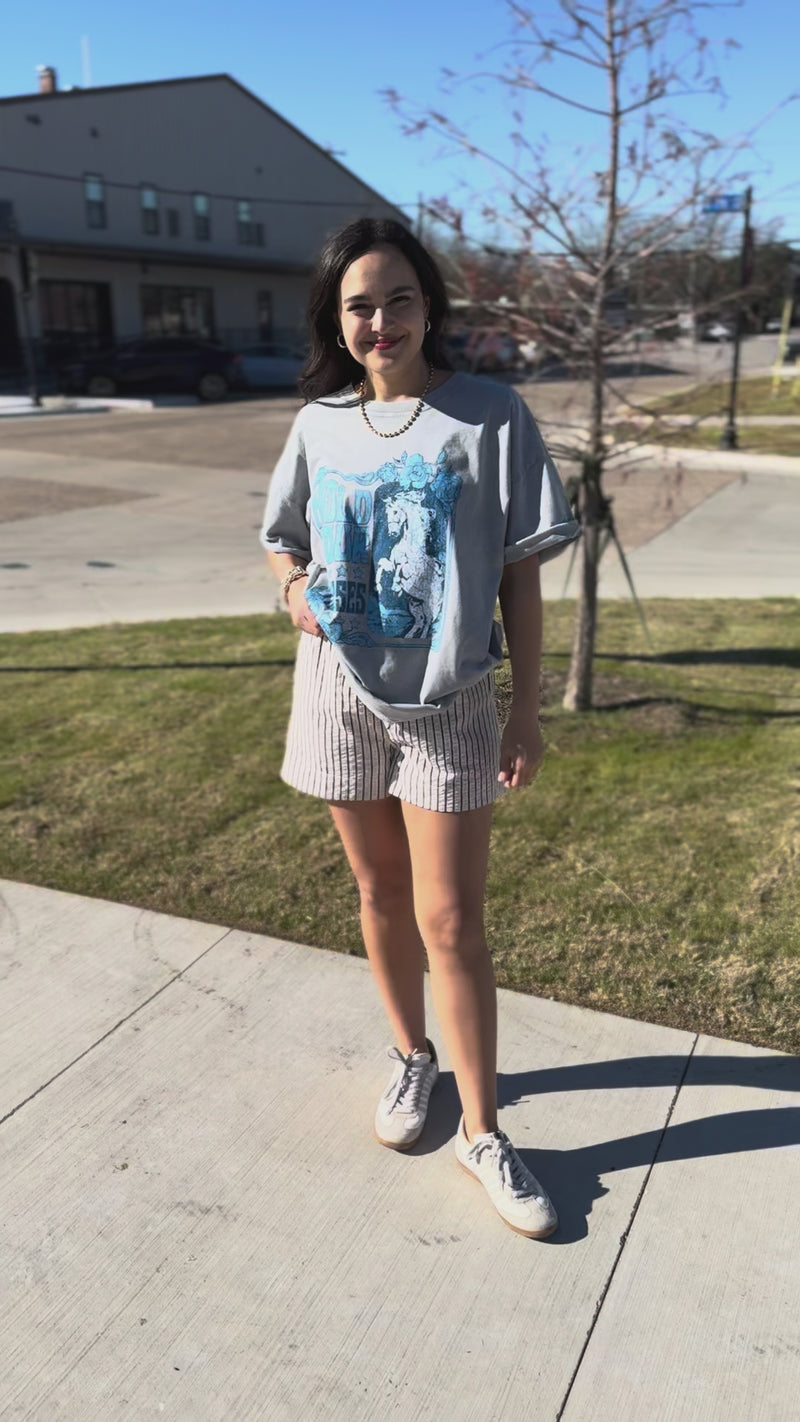 Woman wearing a graphic t-shirt with a horse design outdoors.
