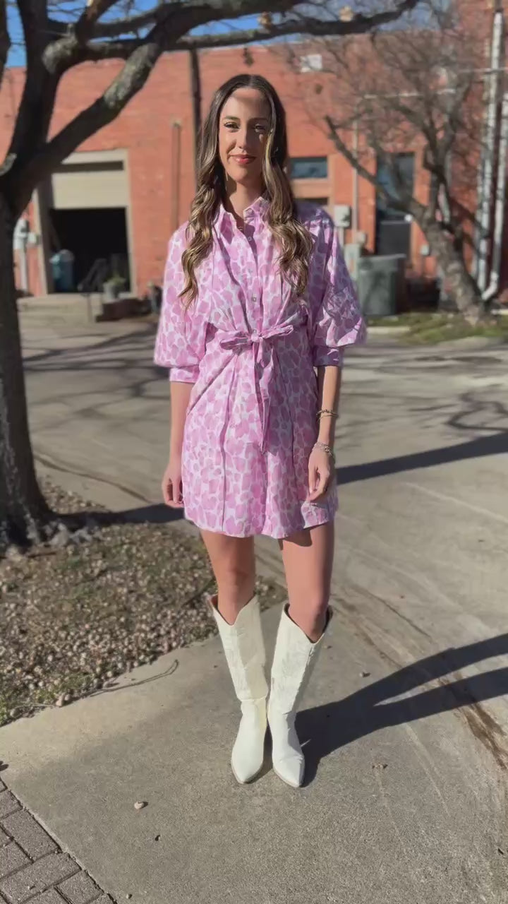 Woman wearing a pink leopard print dress outside.