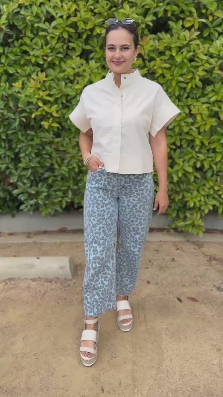 Woman wearing a white blouse and patterned pants outdoors.