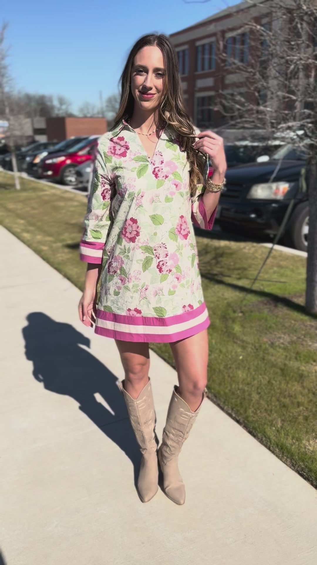 Woman wearing a floral dress with pink accents outside.