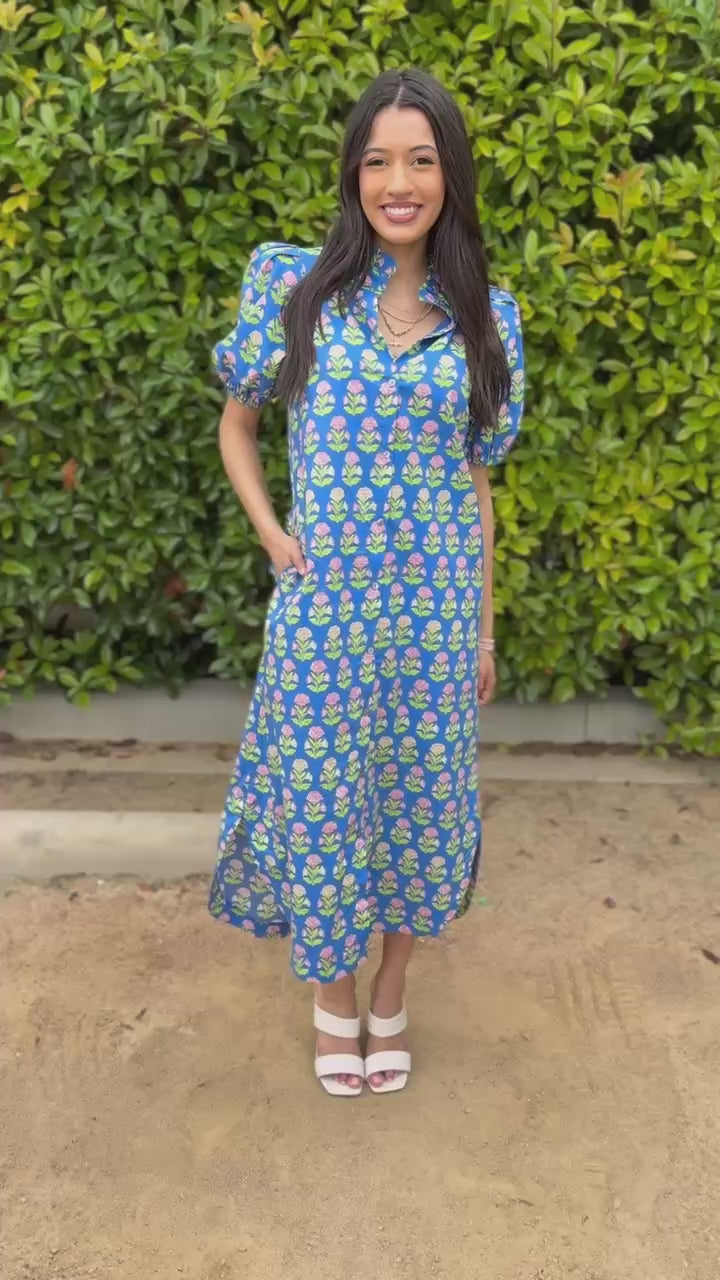 Woman wearing a blue floral dress standing outdoors.