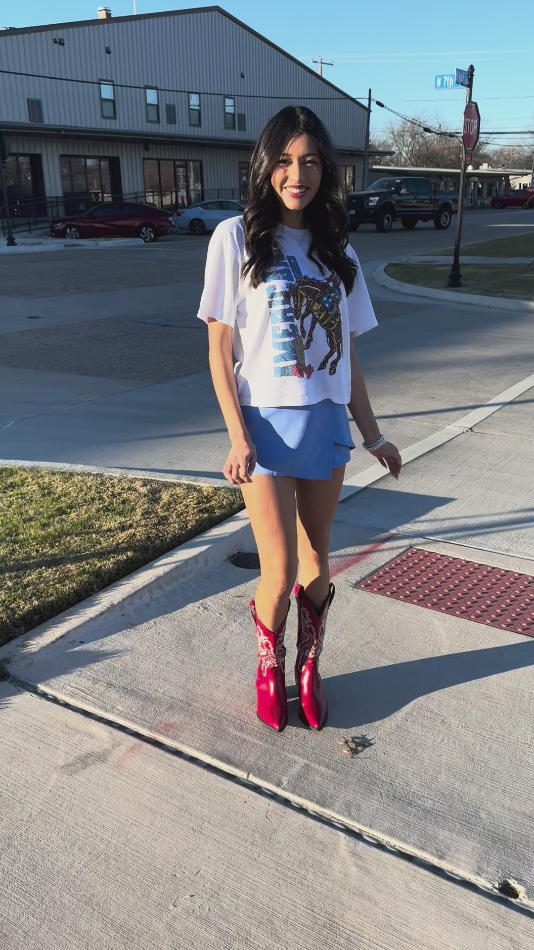 Person wearing a light blue skirt and white shirt with horse design outside.