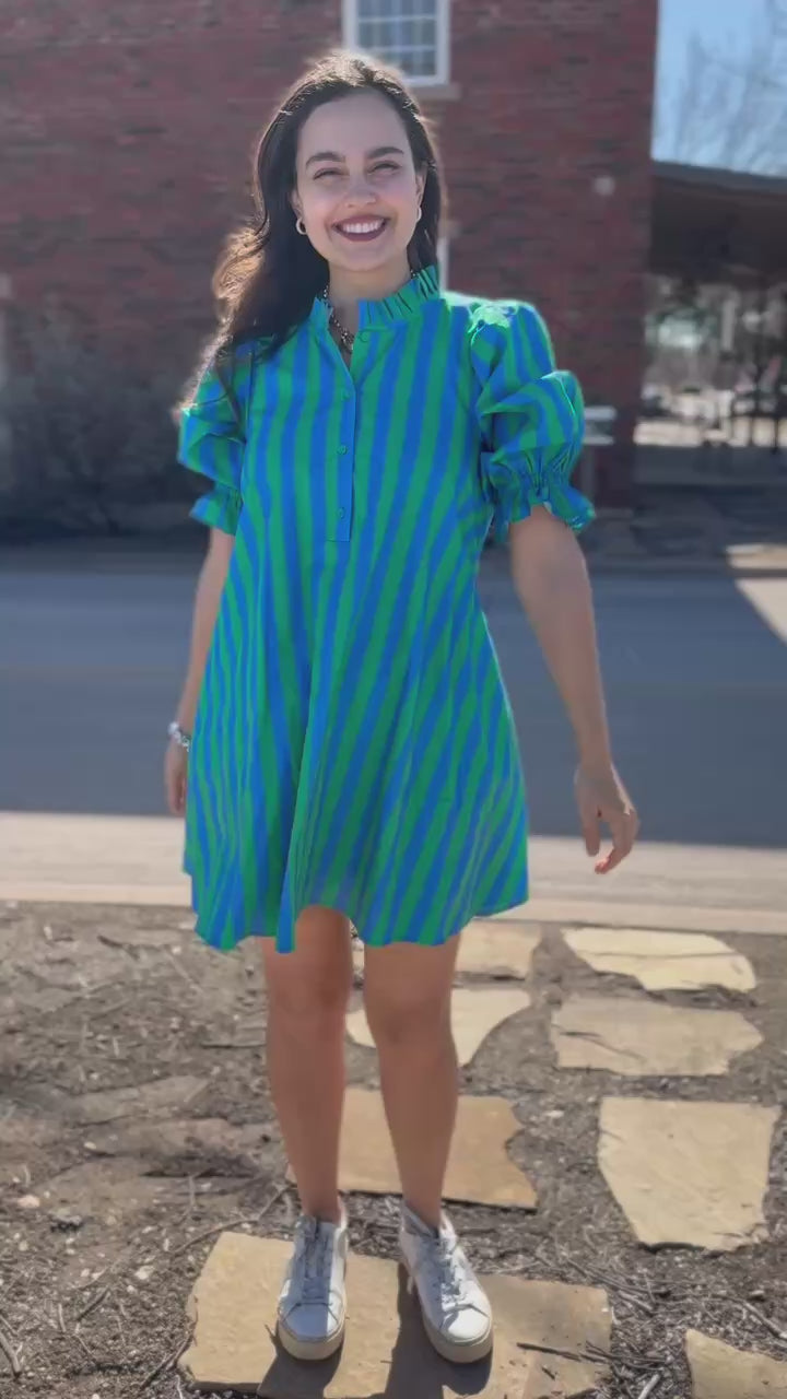 Woman wearing a green and blue striped dress outside.