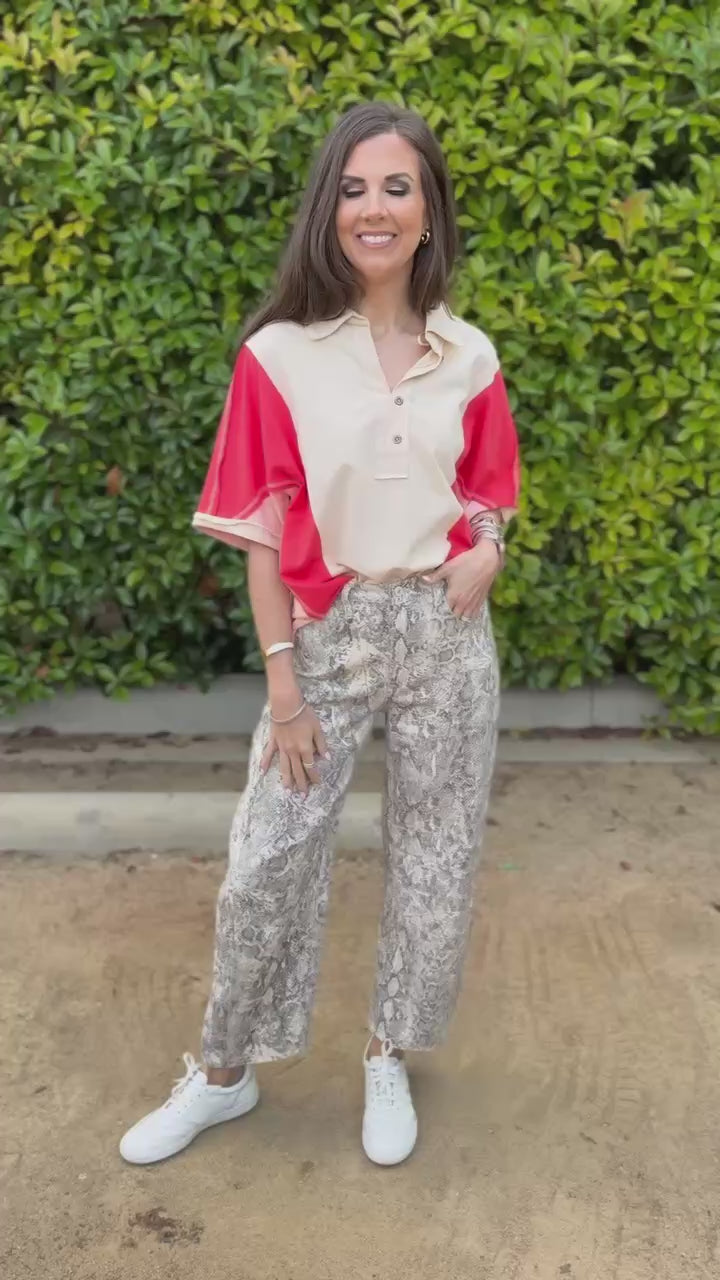Woman wearing a beige and red shirt with patterned pants outdoors.