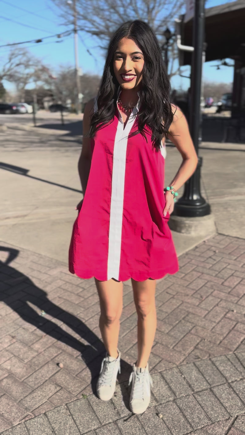 Woman wearing a red dress with a white stripe standing outdoors.