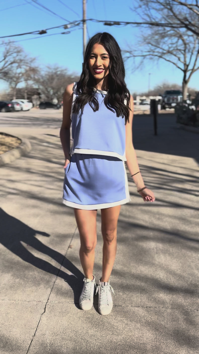 Woman wearing a light blue set with white trim outdoors.