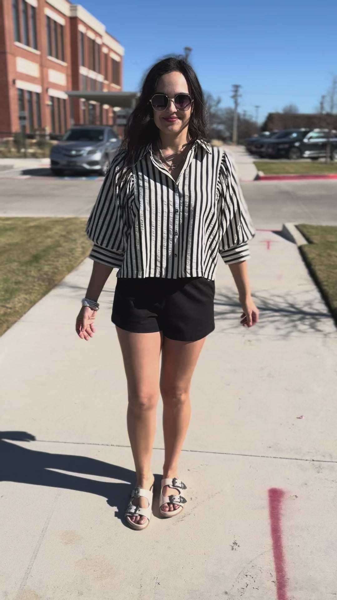 Woman wearing a black and white striped shirt and black shorts outside.