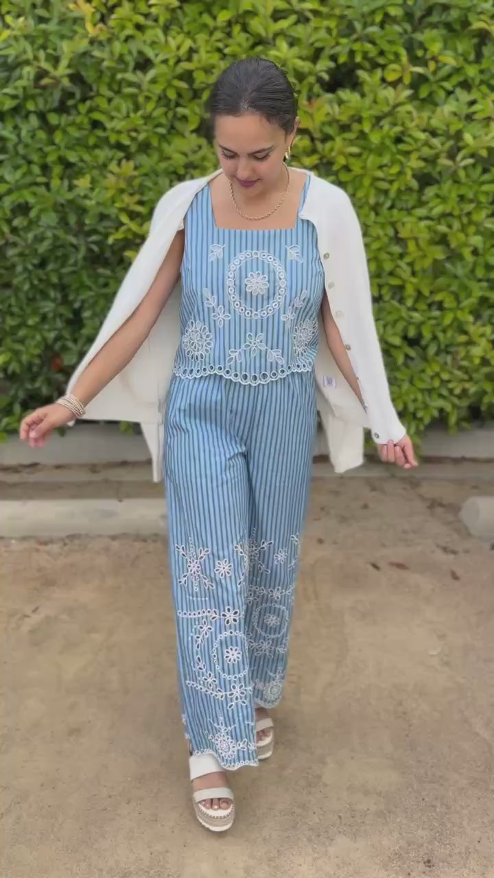 Woman wearing a blue striped outfit with white embroidery outdoors.