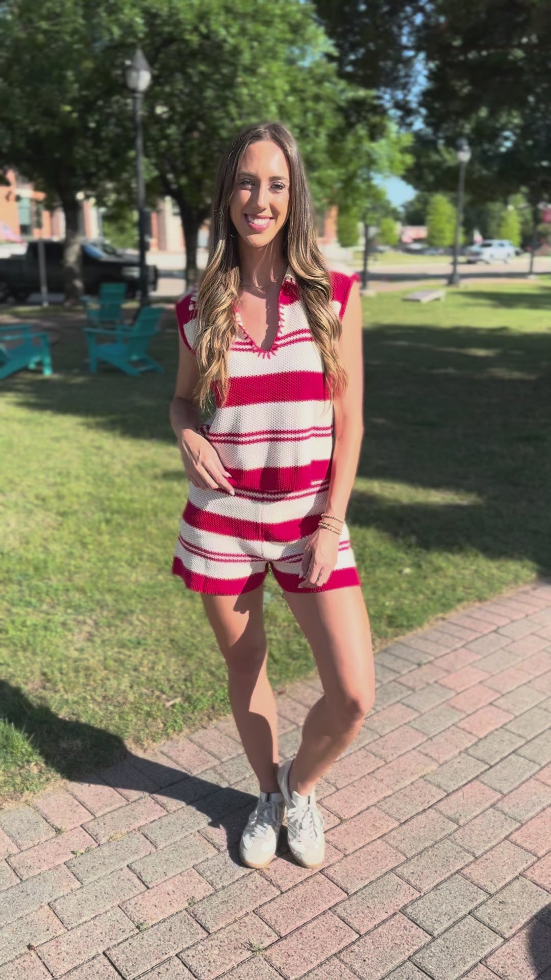 Woman wearing a red and white striped set standing outside.