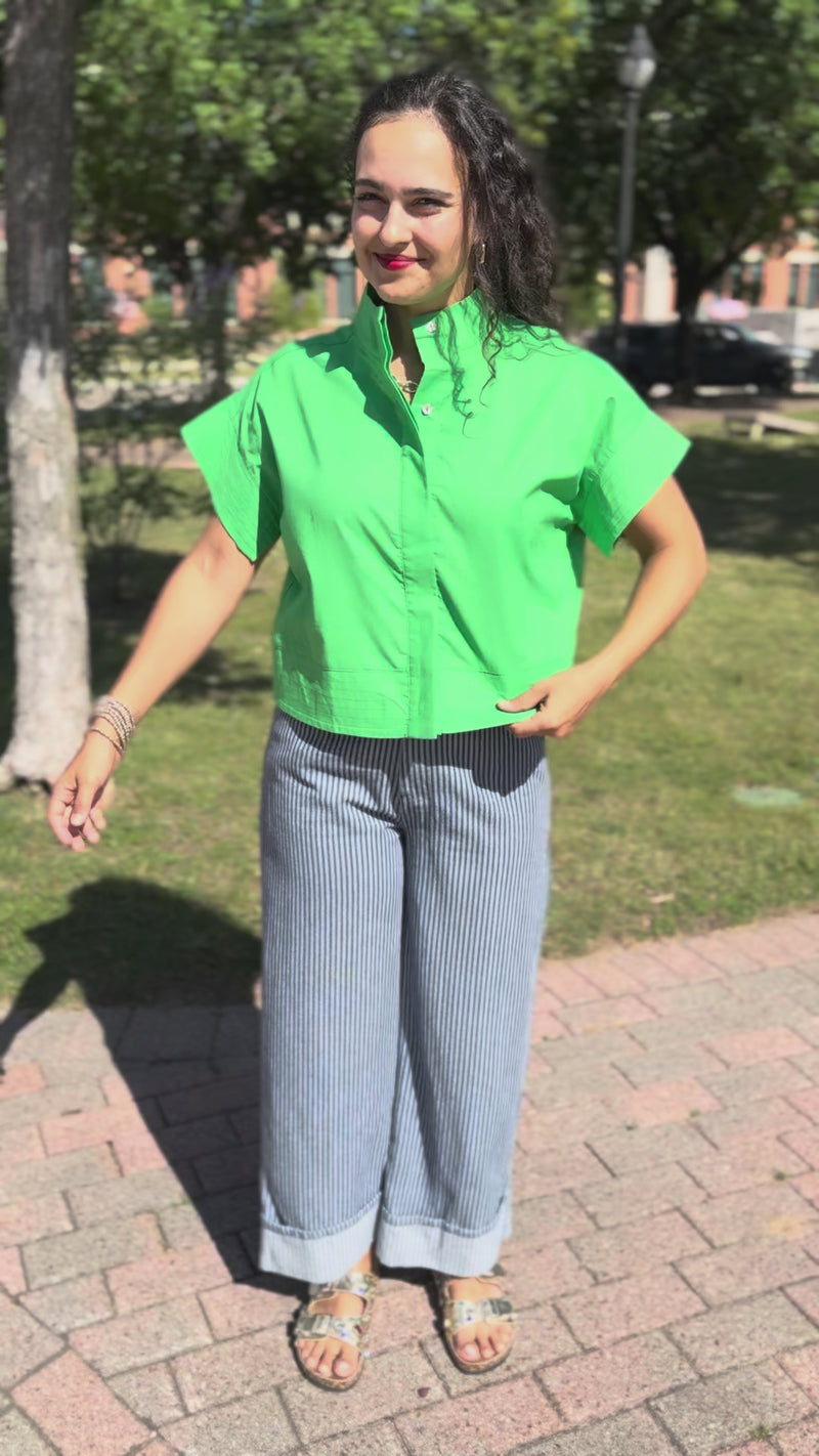 Woman wearing a green top, blue striped pants, and sunglasses outdoors