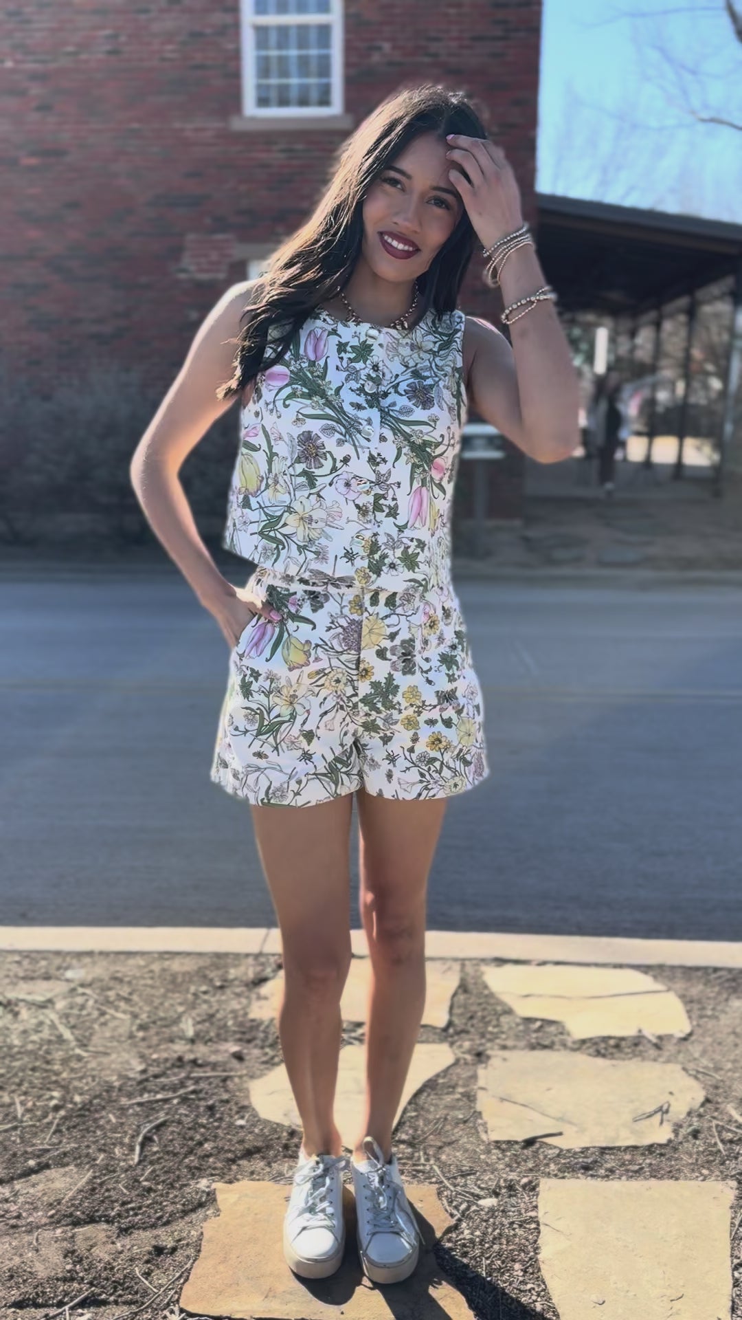 Woman in a floral set standing on a sidewalk with storefronts in the background