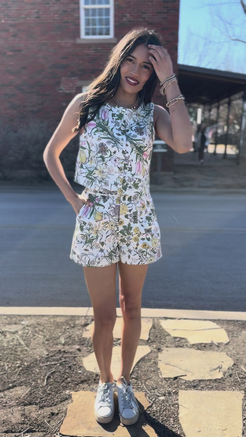 Woman in a floral set standing on a sidewalk with storefronts in the background