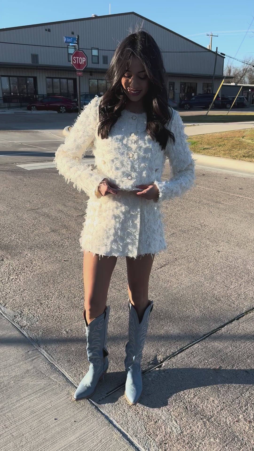 Person wearing a white textured set with fringe details outside.