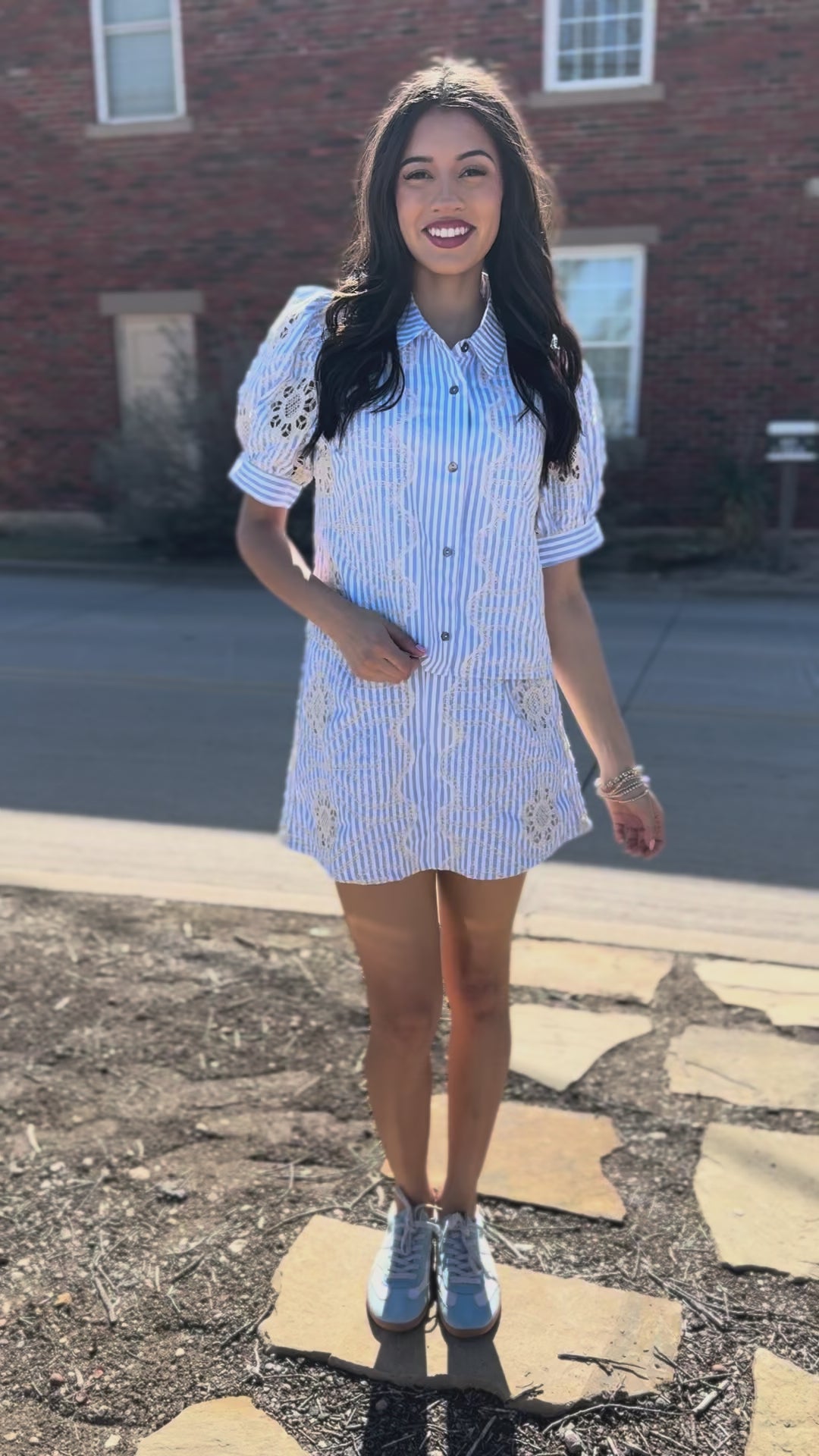 Woman in a matching striped shirt and skirt set standing outside.