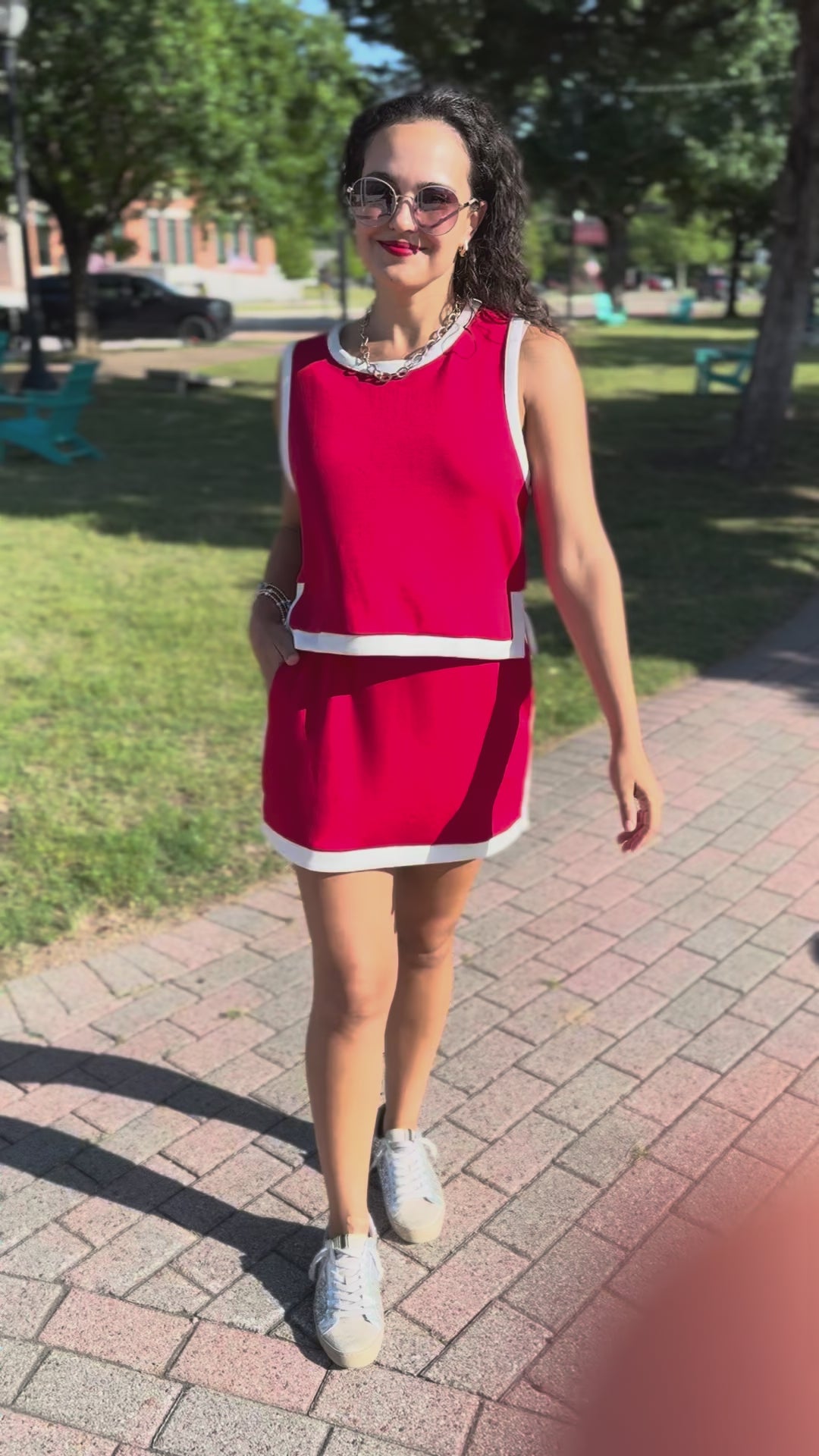 Woman wearing a red set with white trim on a sidewalk.
