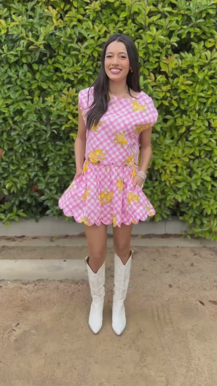 Woman wearing a pink outfit with yellow patterns in an outdoor setting