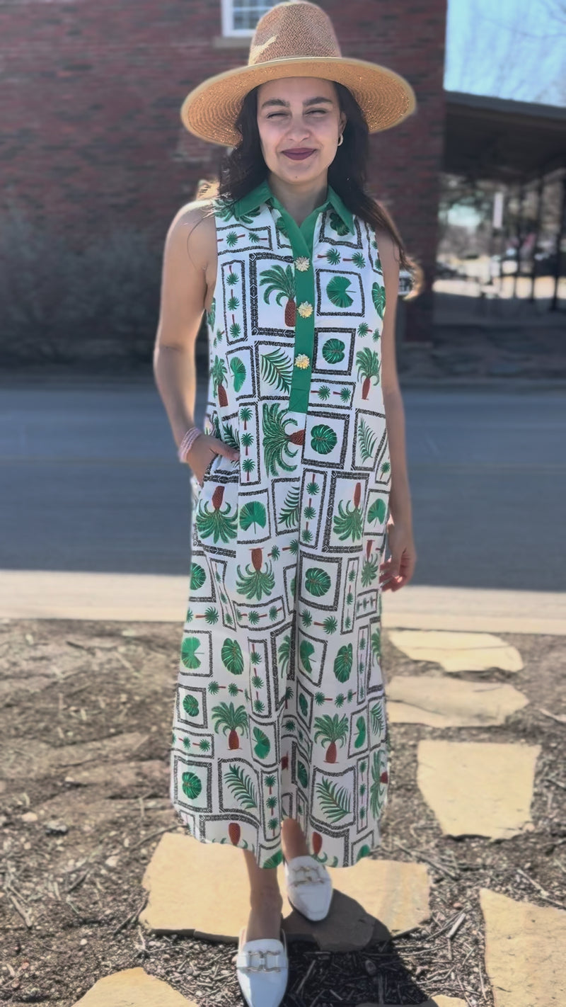 Woman wearing a patterned dress and hat on a city street.