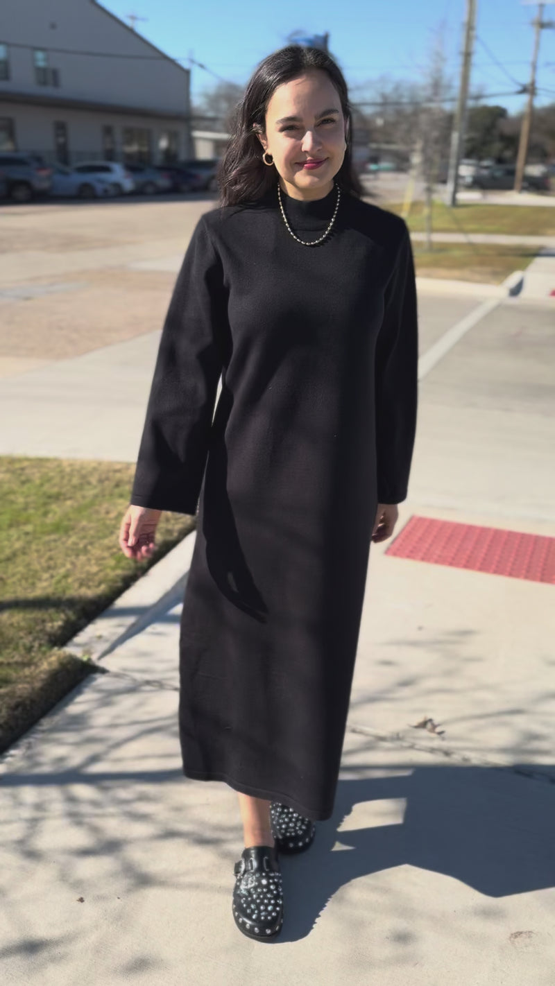 Woman wearing a black dress standing  outside.