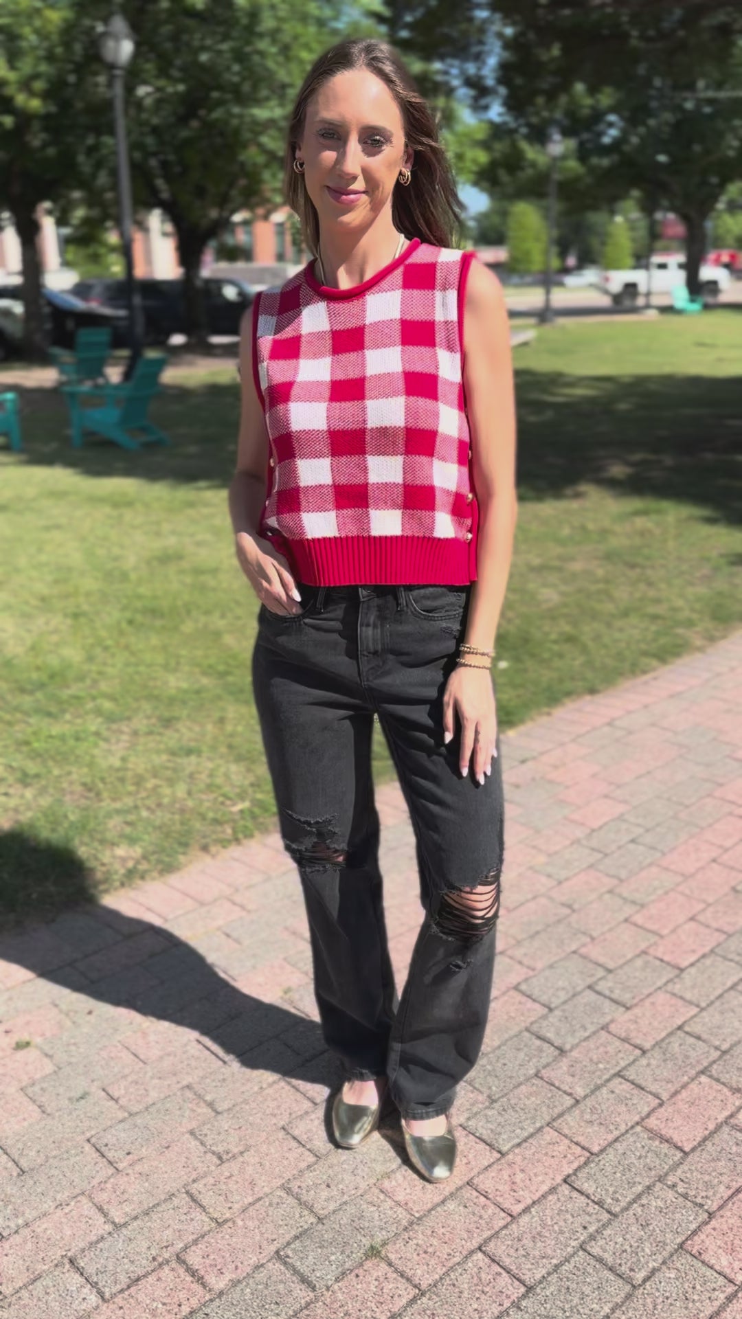 A woman wearing a sleeveless red and white striped vest with a leopard-print neck scarf, light-wash distressed jeans, standing outdoors.