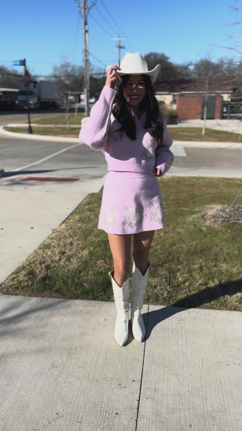 Woman wearing a pink embroidered dress and white cowboy hat outside.
