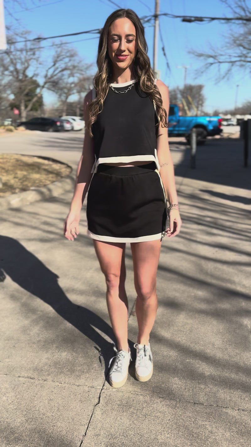 Woman wearing a black and white outfit standing outside.