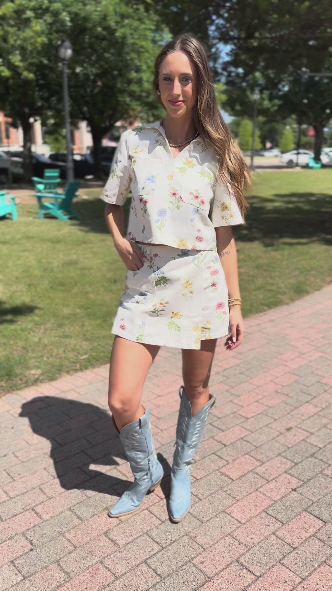 Woman in a floral set standing outside with blue boots.
