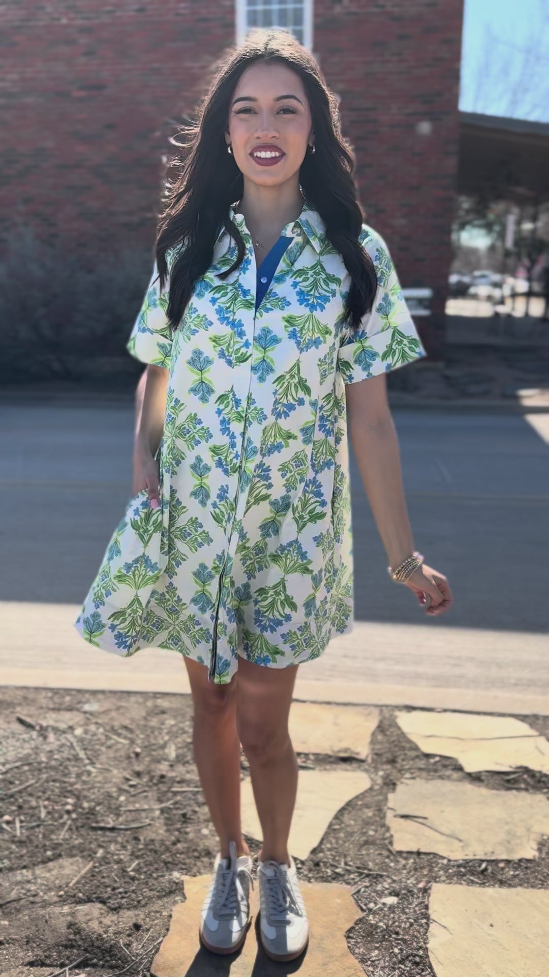 Woman wearing a floral dress standing outside.