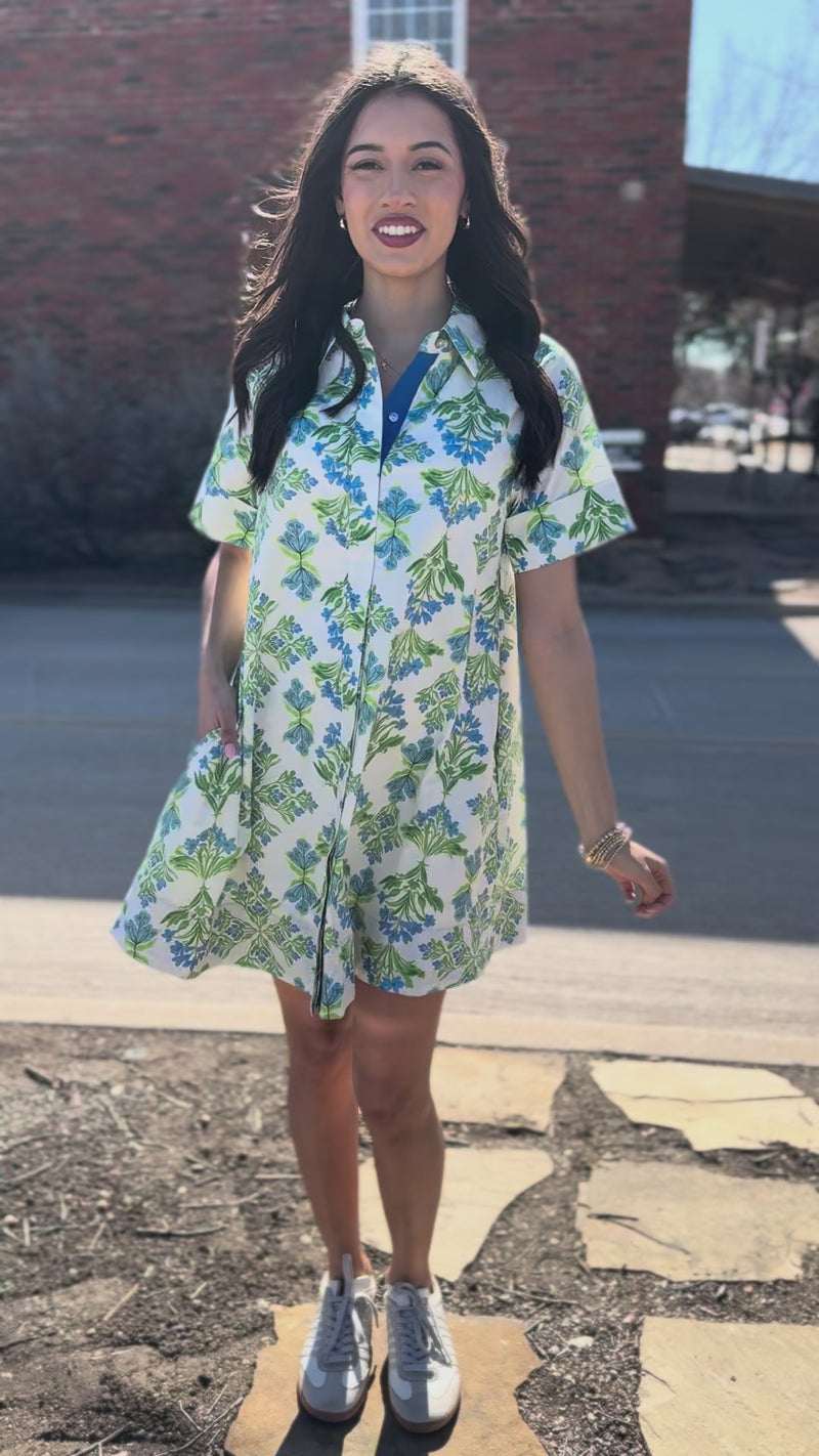 Woman wearing a floral dress standing outside.