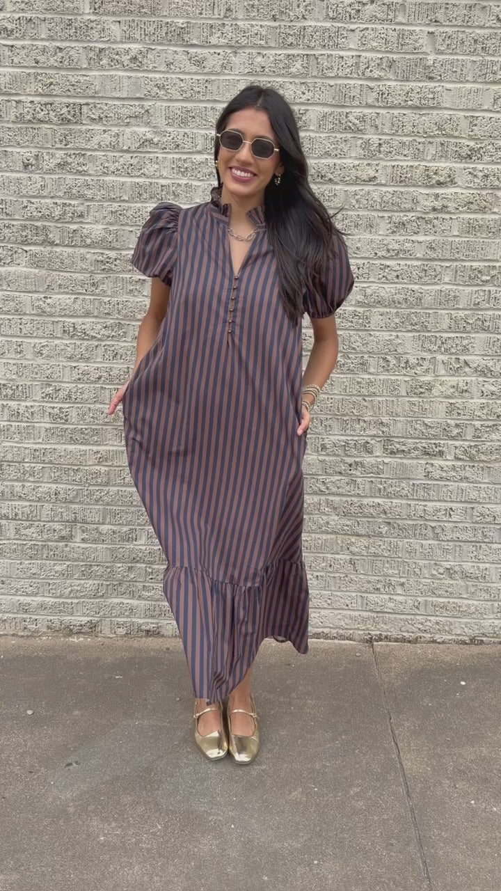 Brunette model wearing a navy and brown dress standing outside. Southern House Clothing